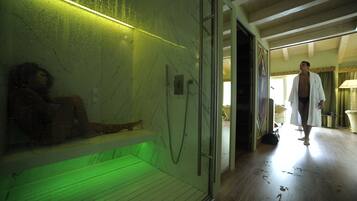 A spa area with a glass-enclosed hot tub, a wooden bench, and a shower area.