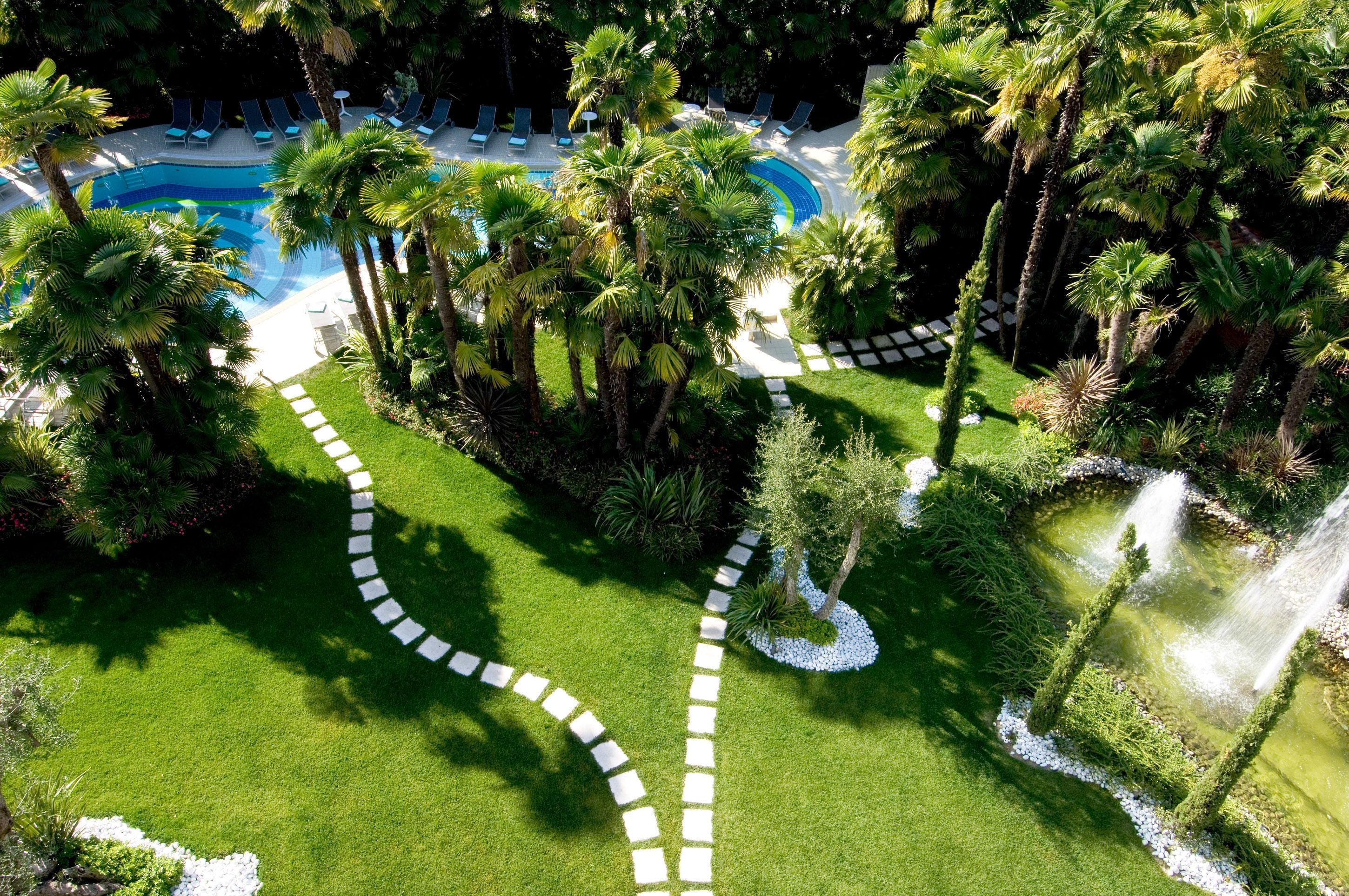 Vista aérea de un resort con piscina, palmeras y un camino sinuoso.