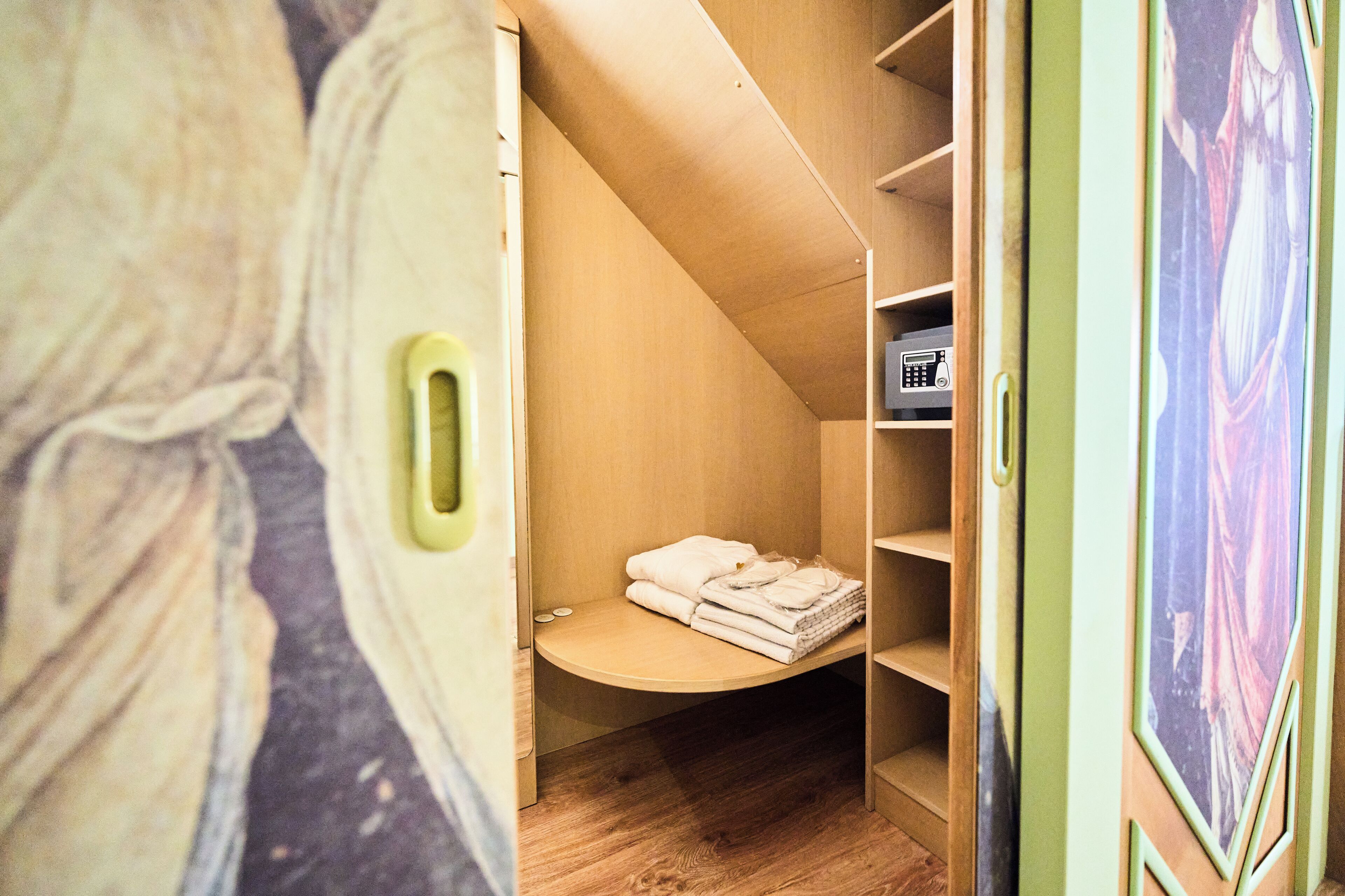 A compact, modern room with a built-in bed, a small seating area, and a shelf with a radio.
