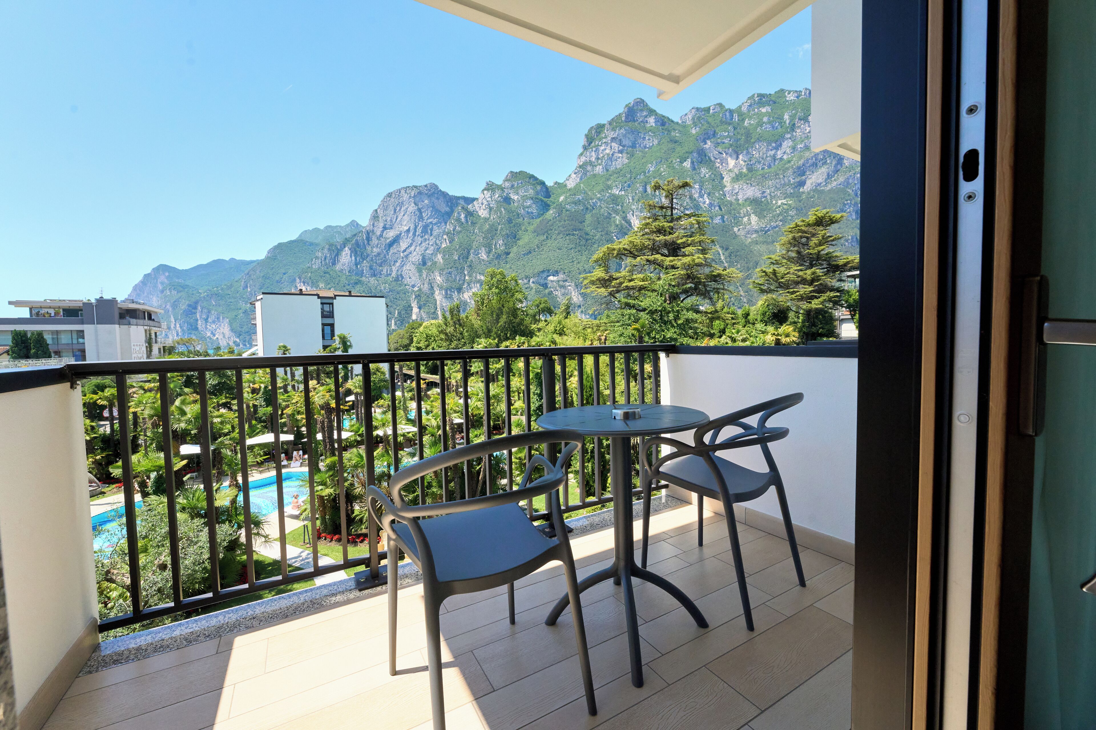 Un balcone con tavolo e sedie, vista su una piscina e montagne.