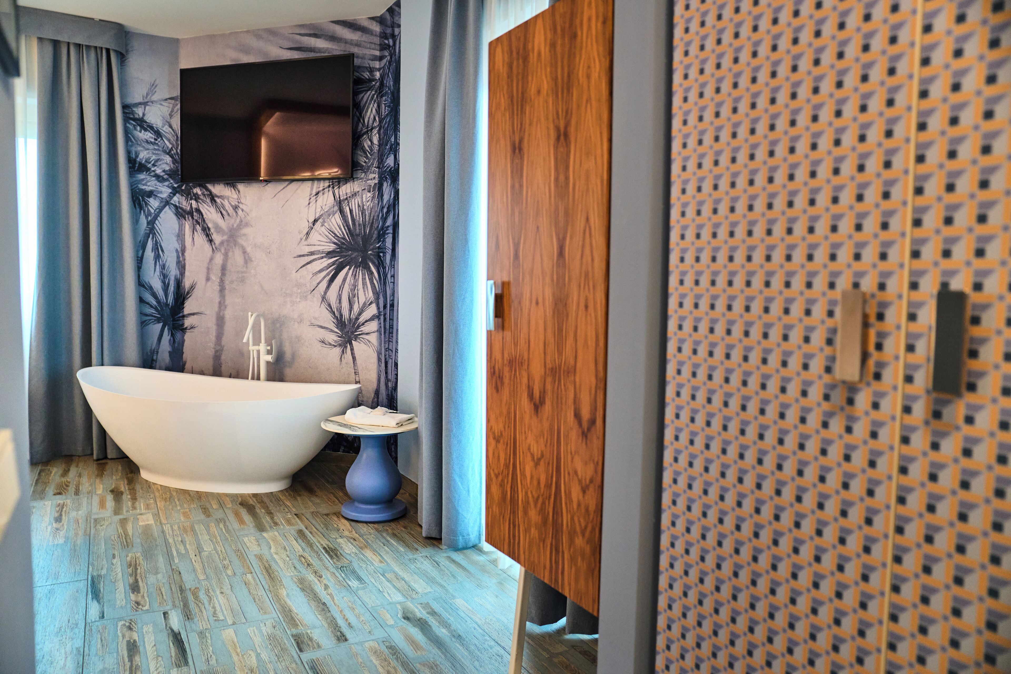 Een moderne badkamer met een vrijstaand bad, een klein rond tafeltje en een houten kast.