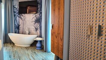 Een moderne badkamer met een vrijstaand bad, een klein rond tafeltje en een houten kast.