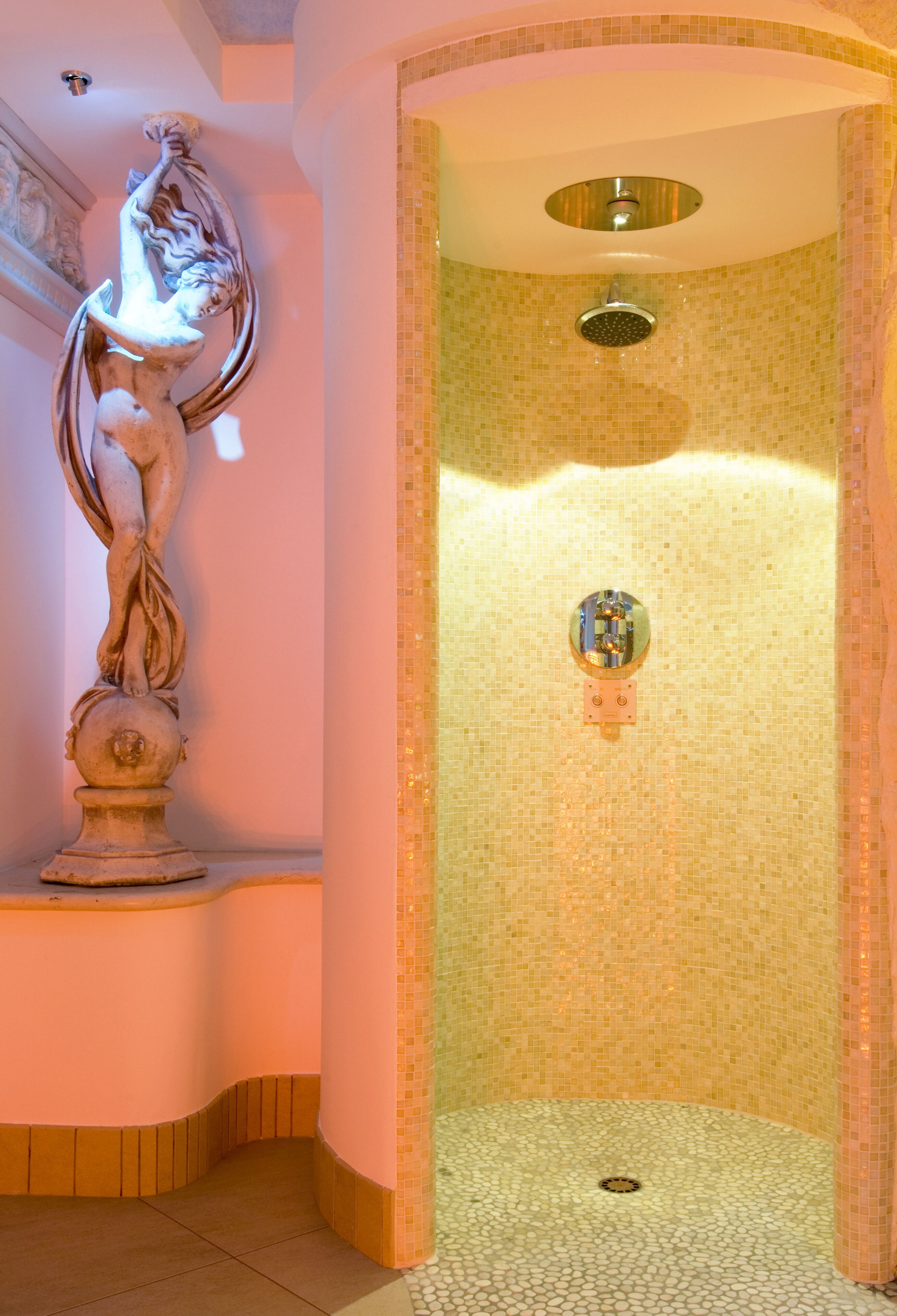 A shower area with mosaic tiling, a statue, and a ceiling light fixture.
