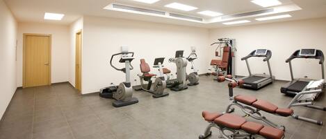 A gym with various exercise equipment including treadmills, elliptical machines, and weight benches.