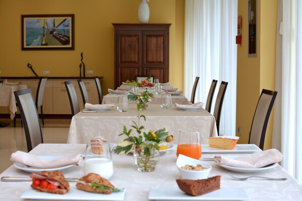 Una mesa de comedor dispuesta para una comida, con diversos platos, vasos y un jarrón con flores.