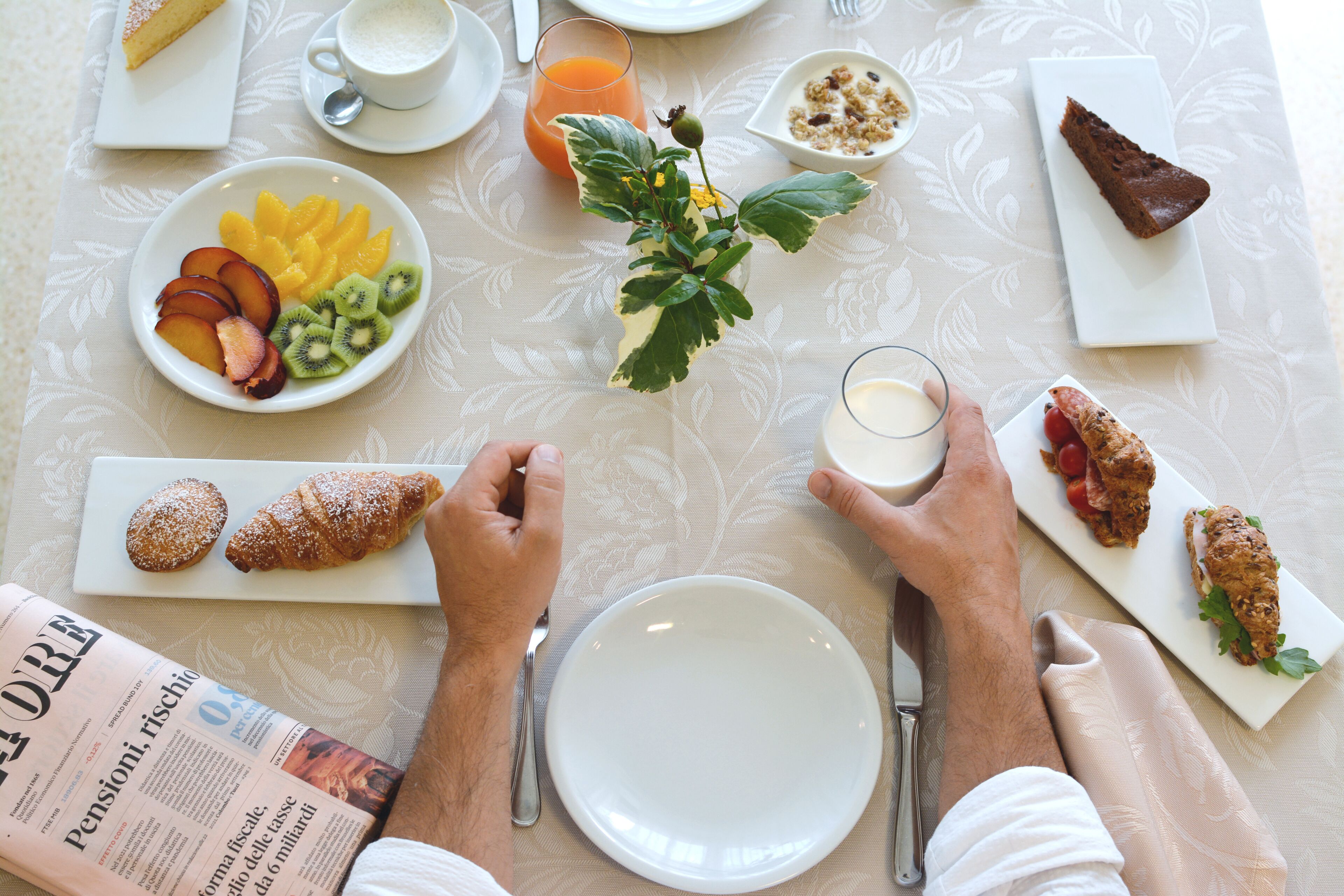 A breakfast setting with plates of food, a glass of juice, and a newspaper.