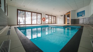 An indoor swimming pool with clear glass windows, a lifebuoy, and a sign on the wall. - Noemys les Terrasses de la Toussuire  (Saint-Pancrace)