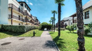 A residential building with multiple balconies, a paved pathway, and palm trees.