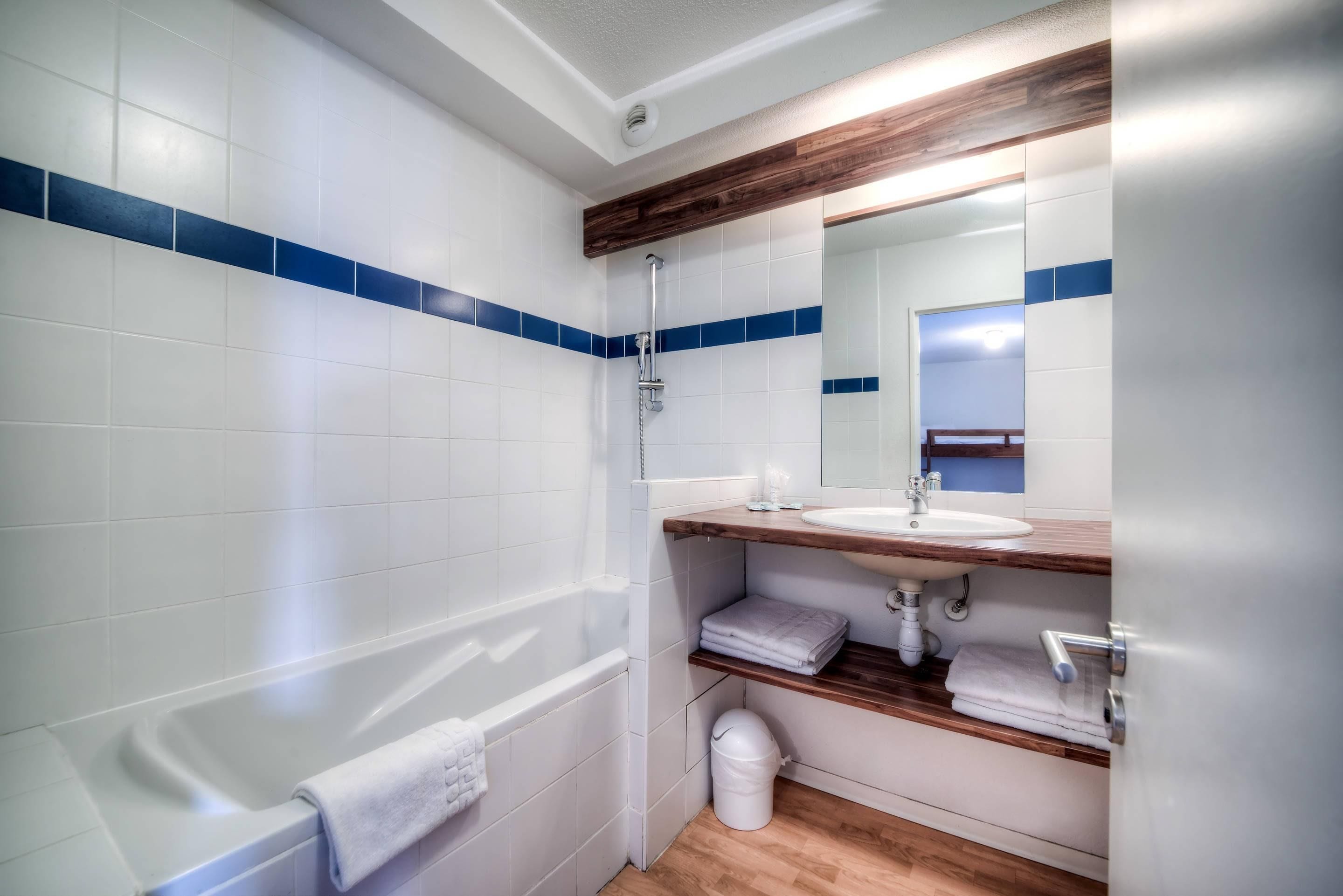 Un baño moderno con bañera, lavamanos y espejo.