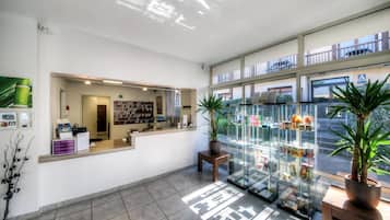 Un espace d’accueil comprenant un comptoir, un panneau d’affichage fixé au mur et une vitrine contenant divers objets.
