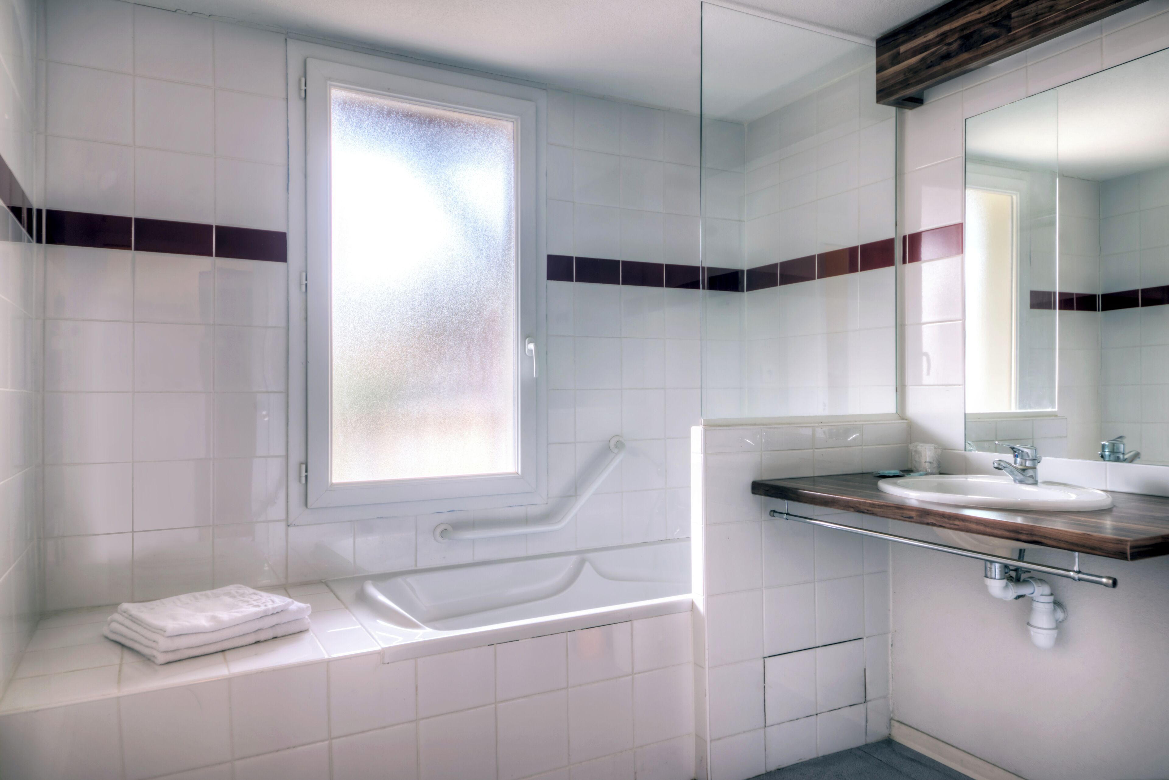 A modern bathroom with a bathtub, a sink, and a mirror.