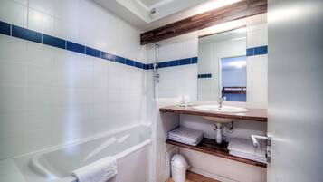 A modern bathroom with a bathtub, a sink, and a mirror.