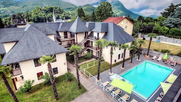 A hotel with multiple buildings, a swimming pool, and a mountainous backdrop.