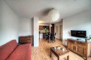 Een moderne woonkamer met een bank, een salontafel, een televisie en een houten kast.