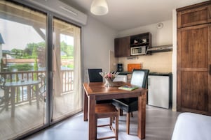 Una cocina compacta con una mesa de comedor, un refrigerador y un microondas.
