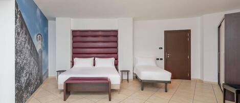 A bedroom with a large bed, a bedside table, a chair, a door, and a wall with a mural.