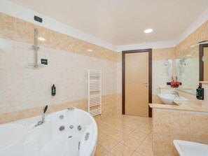A modern bathroom with a large bathtub, a separate sink, a mirror, and a towel rack. - B&B Hotel Settimo Torinese (Settimo Torinese)