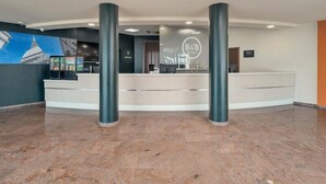 A hotel reception area with a counter, two pillars, and a mural of a building.