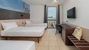 A hotel room with two beds, a desk, a chair, a TV, and a balcony with a view.