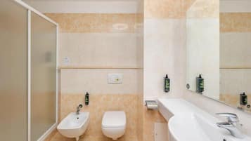 A bathroom with a bidet, toilet, and sink, with a mirror and towel rack.