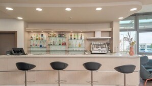 A bar area with a counter, shelves of bottles, and four bar stools. - B&B Hotel Settimo Torinese (Settimo Torinese)