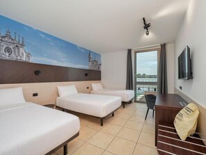 Habitación de hotel con dos camas, un escritorio, una silla, un televisor y un mural de un edificio.