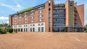 A B&B hotel with a brick facade, multiple floors, and a large parking area.