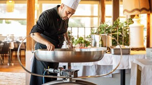 A chef preparing food in a professional kitchen with stainless steel equipment and a large wok. - VOI Tanka Village (Villasimius)