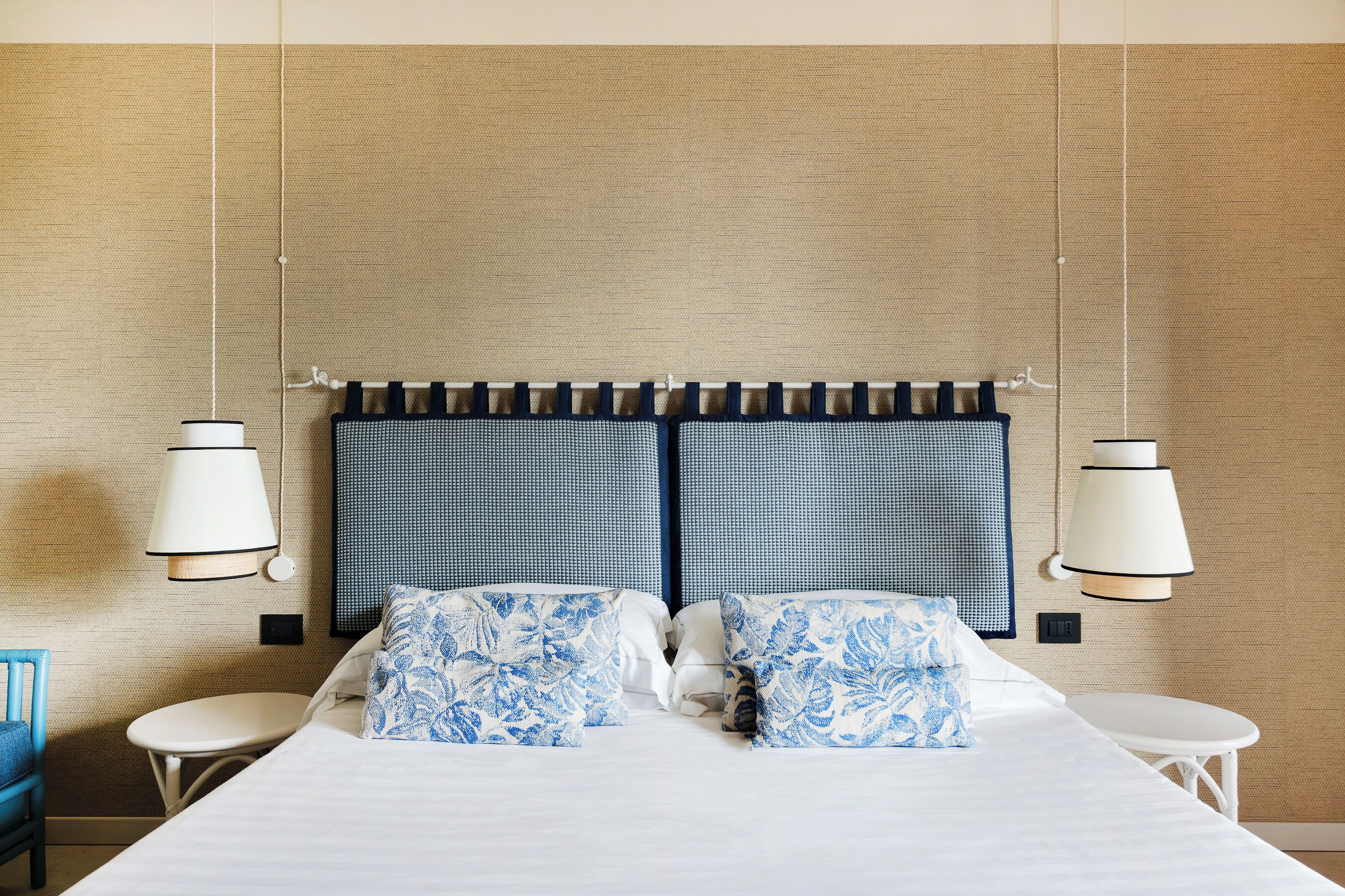 Una habitación de hotel con una cama, dos mesitas de noche y un cabecero azul y blanco estampado.