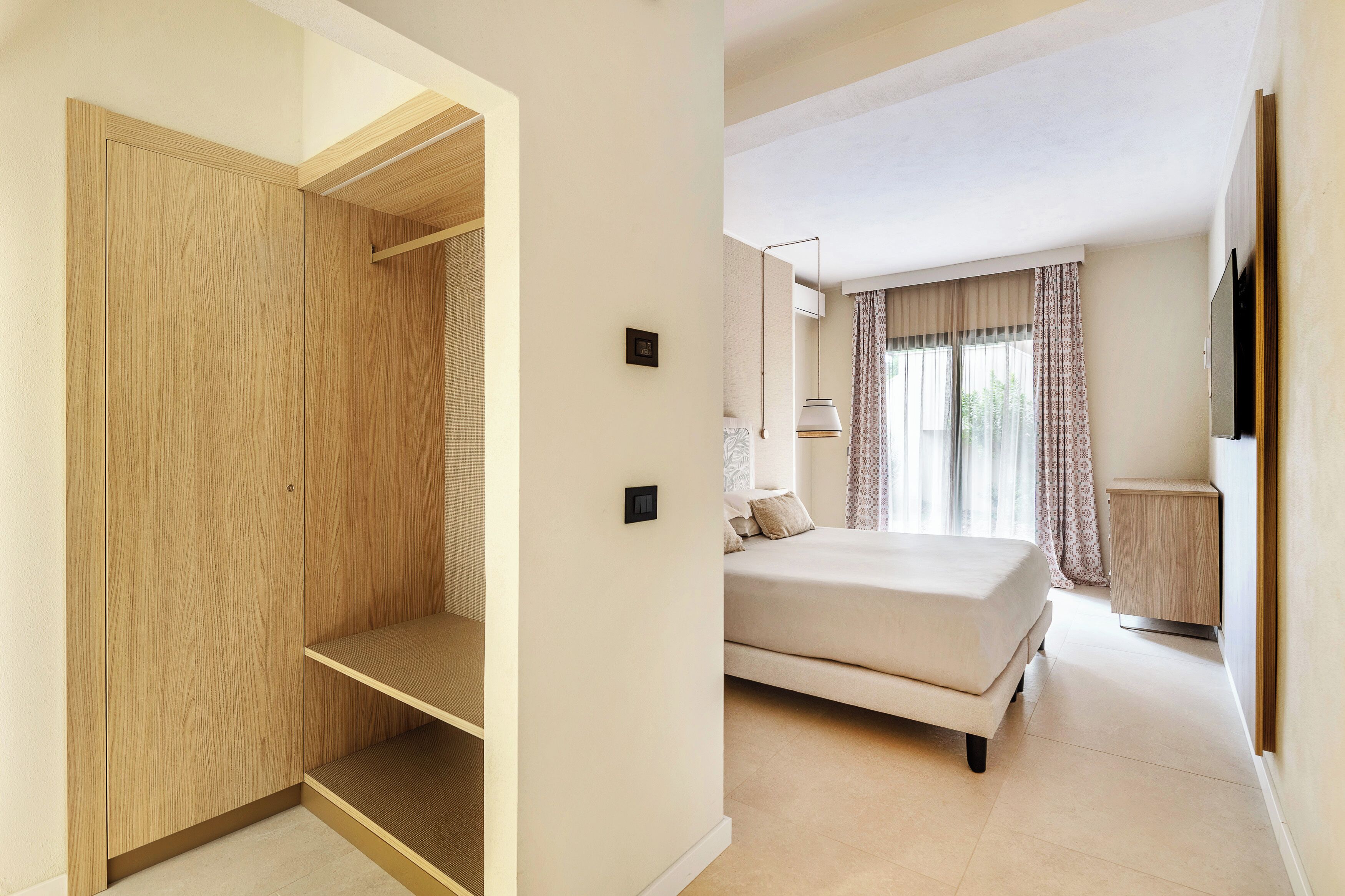 A bedroom with a bed, a wardrobe, a bedside table, and a TV.