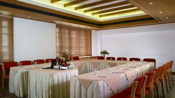 A conference room with a long table, red chairs, and a projector.