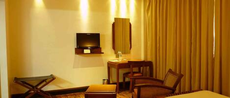 A hotel room with two beds, a desk with a chair, a television, and a mirror.