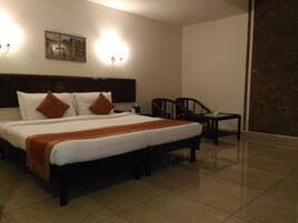 Una habitación de hotel con una cama grande, dos sillones, una mesita y un cuadro en la pared.
