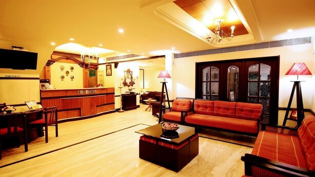 A hotel lobby with a reception desk, seating area, and a reception sign. - Yuvarani Residency (Kanayannur)