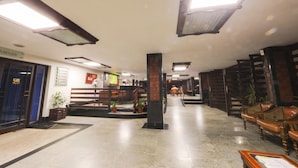 A spacious lobby with a reception desk, seating area, and a staircase leading to upper floors. - Bharat Hotel (Kanayannur)