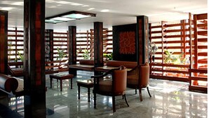 A spacious lobby with high ceilings, a central seating area with sofas and tables, and a large abstract painting on the wall. - Bharat Hotel (Kanayannur)