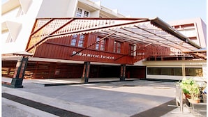 A hotel with a distinctive red and white facade, a covered entrance, and a paved courtyard. - Bharat Hotel (Kanayannur)