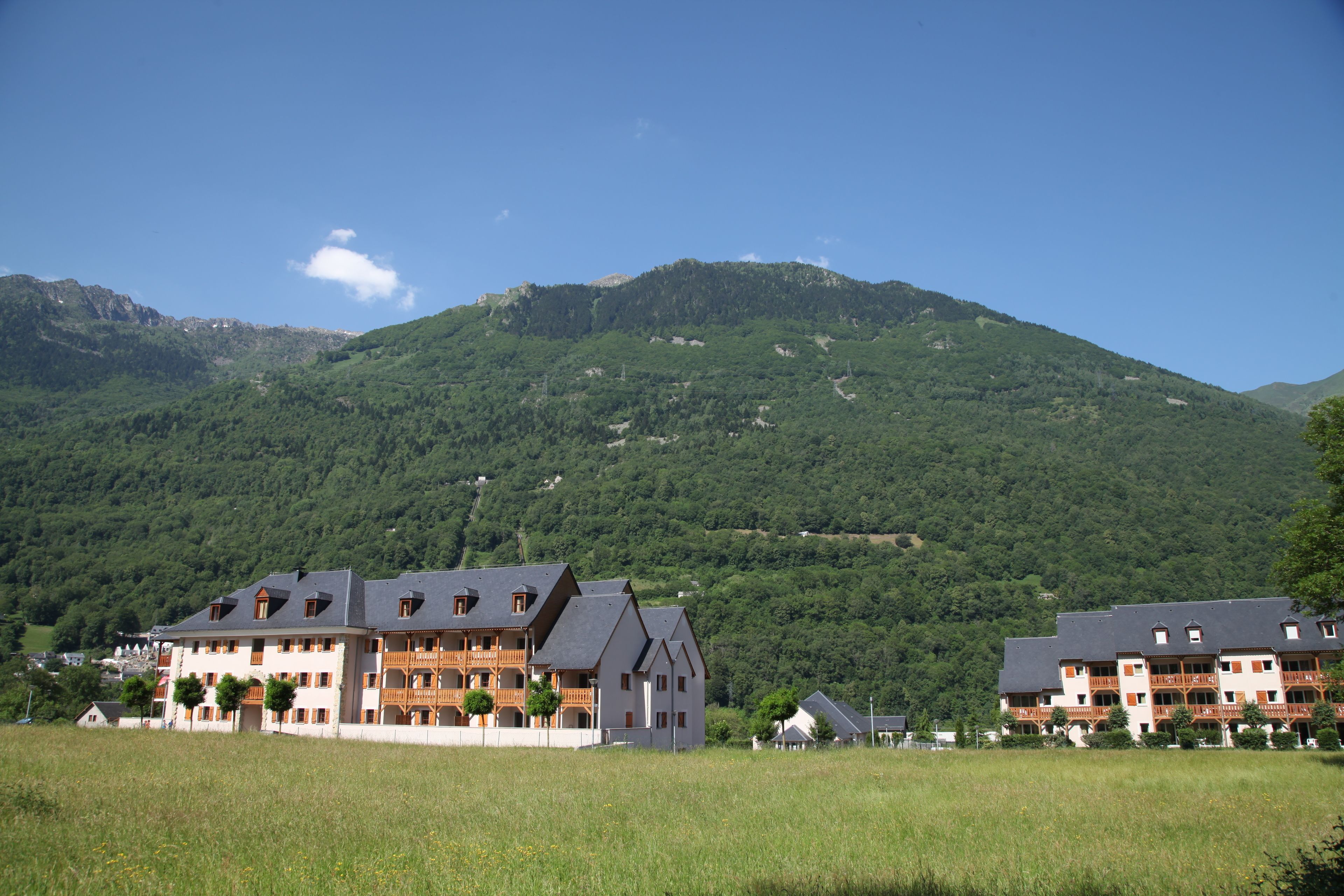Ein Hotel mit mehreren Etagen, Balkonen und einer Bergkulisse.