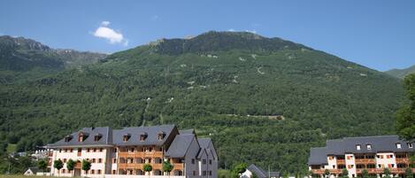 A hotel with multiple floors, balconies, and a mountainous backdrop.
