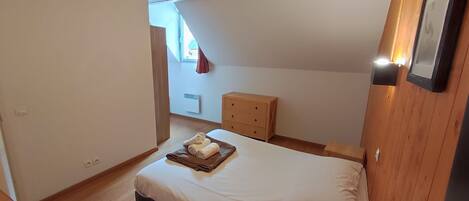 Un dormitorio con cama, cómoda de madera y lámpara en el techo.