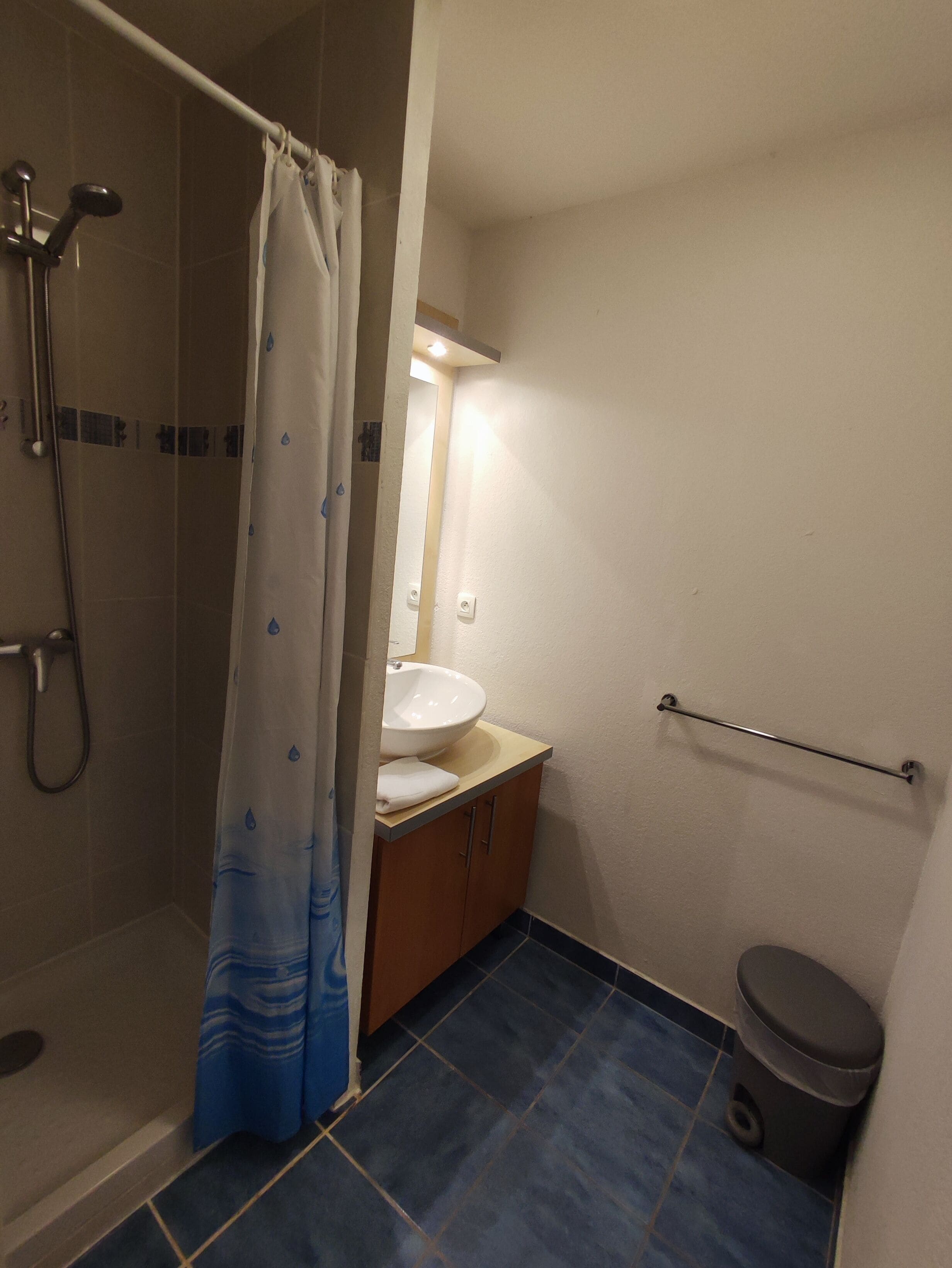 Ein Badezimmer mit Dusche, Waschbecken, Toilette und Haltegriff.