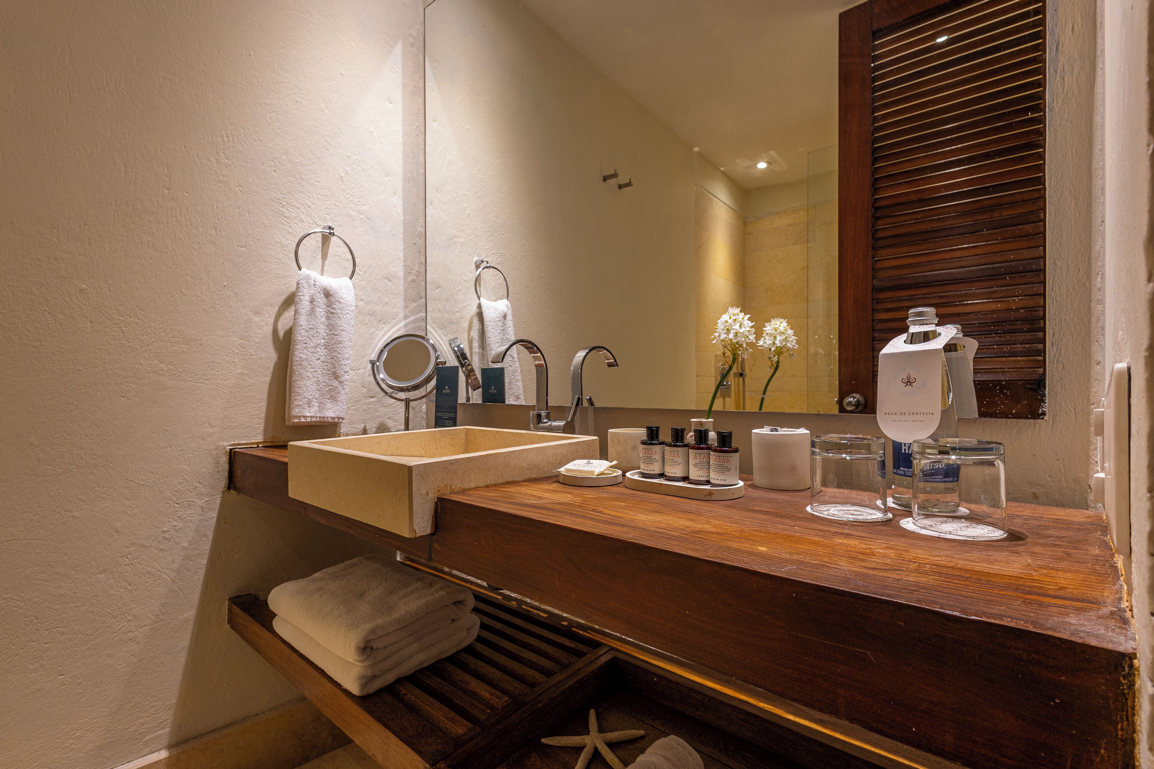 A bathroom with a wooden vanity, a large mirror, a sink, and a towel rack.