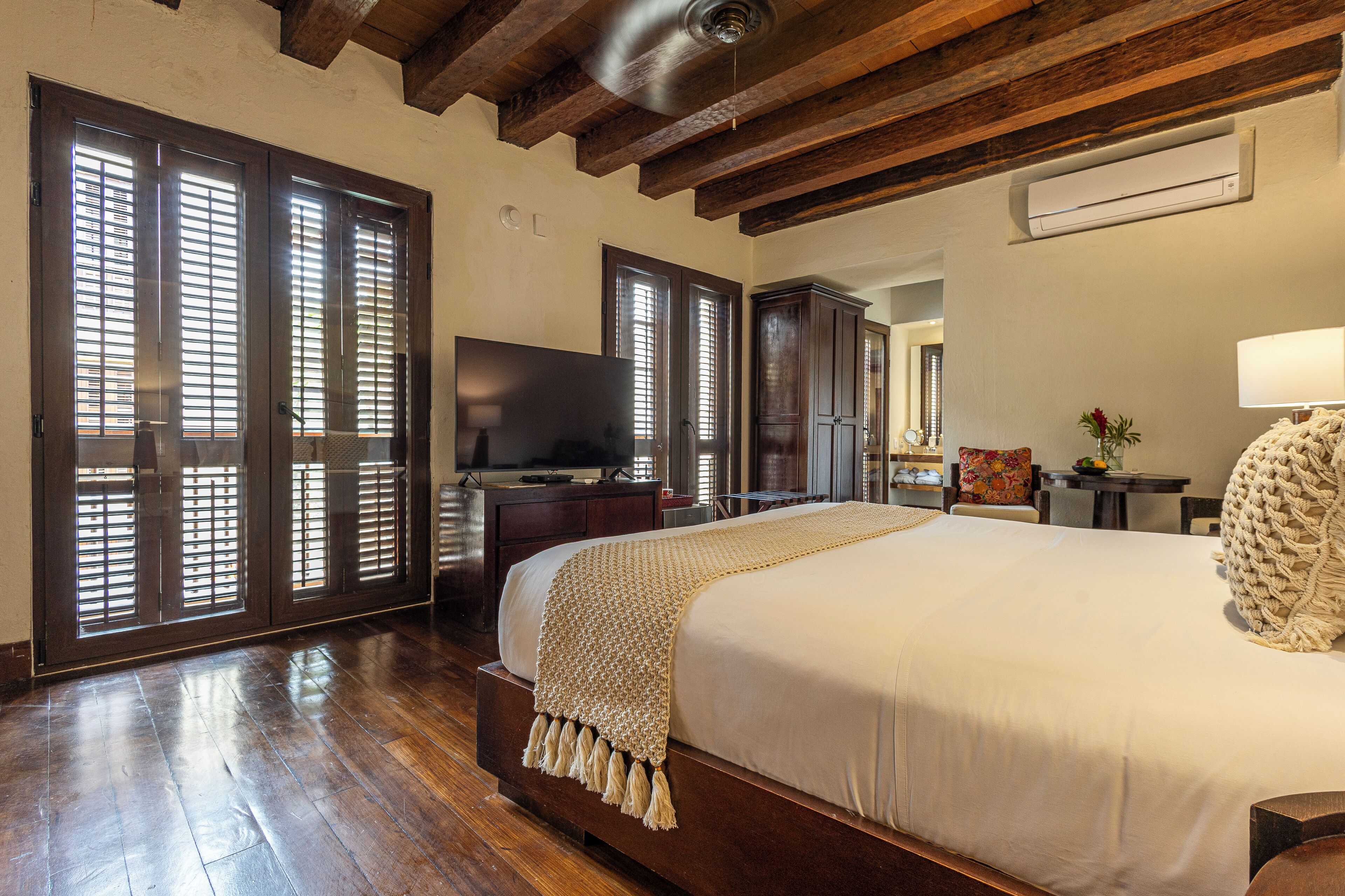 Une chambre spacieuse avec un grand lit, un plancher en bois et un ventilateur de plafond.