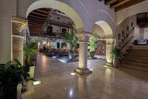 A spacious lobby with a high ceiling, stone columns, and a central fountain.