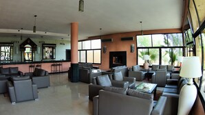A spacious lobby with multiple seating areas, a bar, and large windows offering natural light.