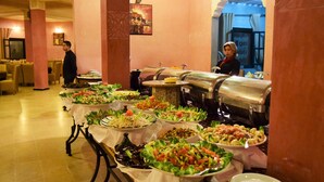 A buffet setup with various dishes, a buffet line, and a person serving.