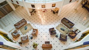 A spacious atrium with multiple seating areas, a central staircase, and a high ceiling with natural light. - Metropole Hotel Kampala (Kampala)