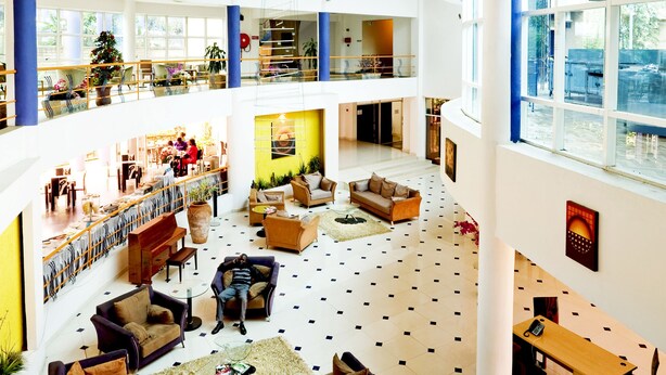 A spacious, multi-level atrium with a central seating area, high ceilings, and large windows. - Metropole Hotel Kampala (Kampala)