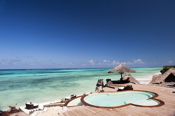 A tropical resort with a wooden deck, a heart-shaped pool, and thatched umbrellas. - Karafuu Beach Resort & Spa (Michamvi)