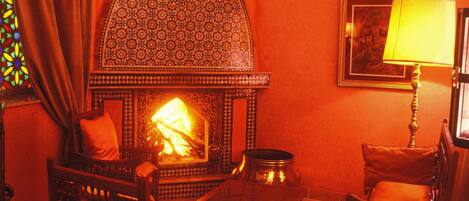A cozy room with a fireplace, patterned wall, and traditional furniture.